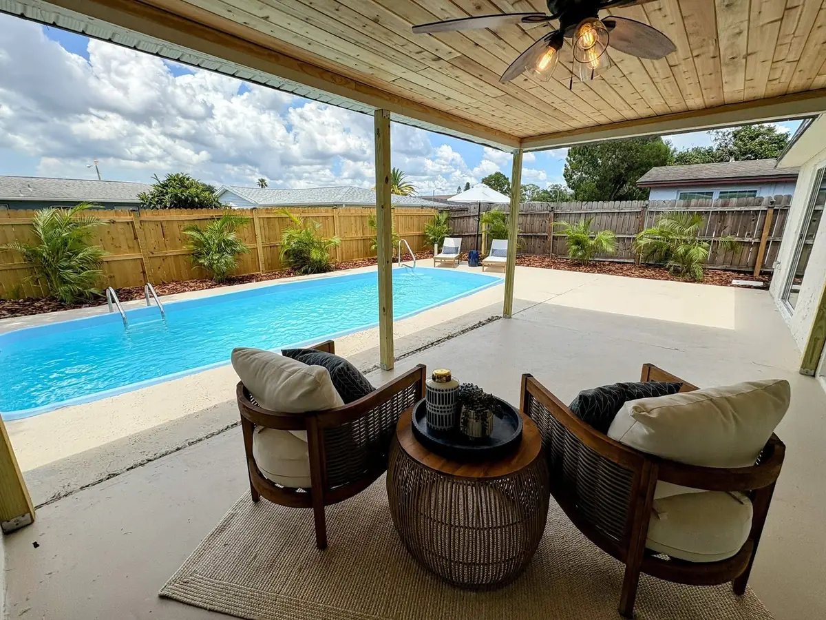 Looking out from a new covered patio, past lounge chairs, to a freshly finished pool