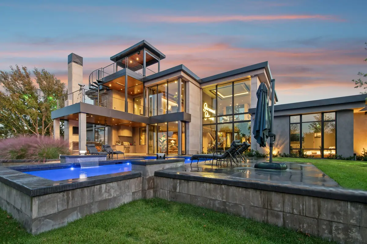 Inspiration photo: a modern home with a lit pool and raised spa at dusk (not a Liquid Lux or Seamco project)